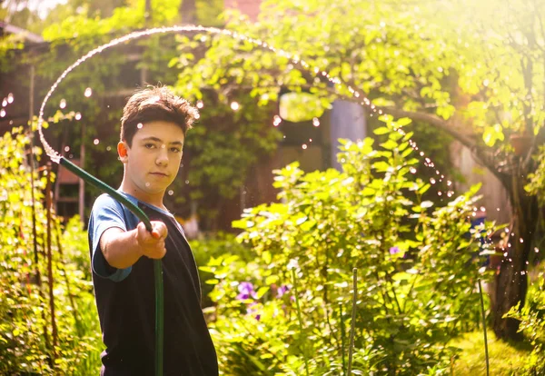 아이 손을 잡고 여름 맑은 녹색 정원에서 물을 뿜어 호스 — 스톡 사진