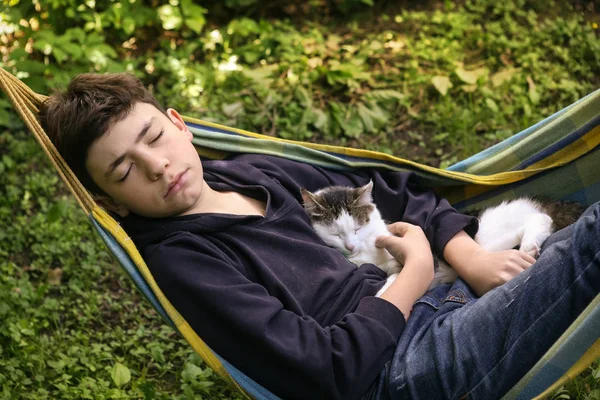 Tiener jongen met kat in hummock nap — Stockfoto
