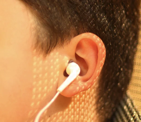 Closeup photo of boys ear with earphone — Stock Photo, Image