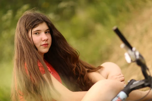 Девочка-подросток едет на велосипеде по проселочной дороге через лес — стоковое фото