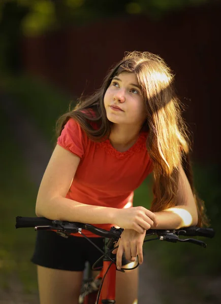 少年女孩骑自行车在乡间小路穿过森林 — 图库照片
