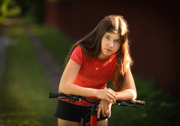 Adolescente menina passeio de bicicleta na estrada rural através da floresta — Fotografia de Stock