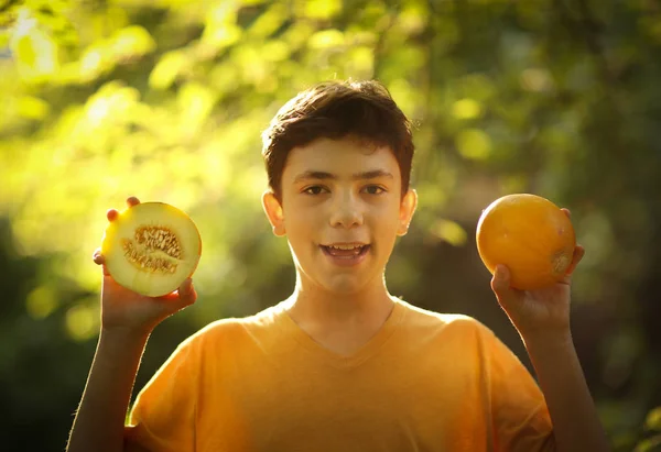 Tonåring pojke äter halv skär mogen melon med sked — Stockfoto