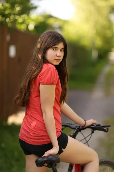 Adolescente menina passeio de bicicleta na estrada rural através da floresta — Fotografia de Stock