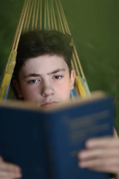 Adolescente ragazzo lettura in amaca — Foto Stock