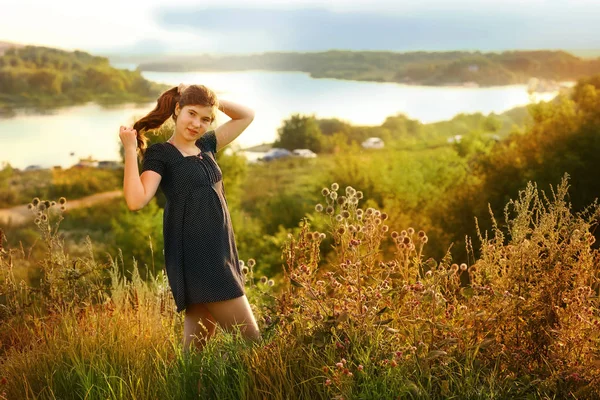 夏の川の風景の背景水平写真に水玉ドレスで長い茶色の髪を持つティーンエイジャーの女の子 — ストック写真