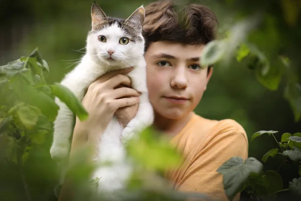 少年男孩拥抱猫在绿色庭院背景特写照片 — 图库照片