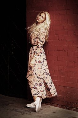 güneş gözlüğü kırmızı kare tuğla duvar zemin üzerine çiçek baskı elbiseli kadınla güzel sarışın turist