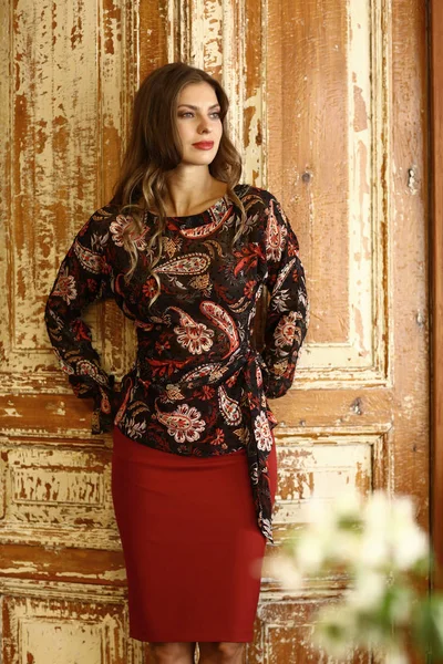 fashion model girl in formal print blouse and red skirt, bag in stylish interior close up photo
