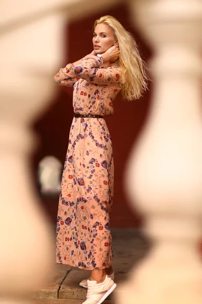 beautiful blond tourist woman with sun glasses in floral print dress on Red Square brick wall background