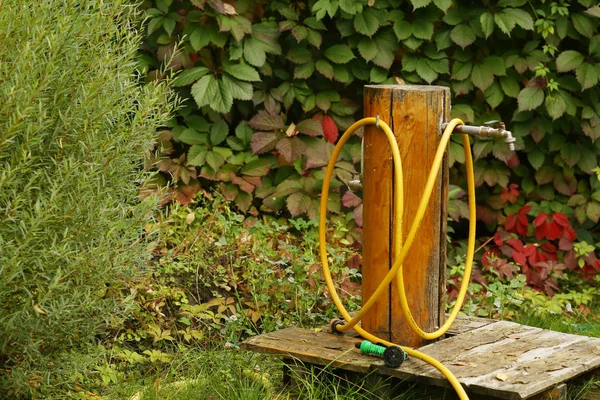 Water well creative outlet with hose close up photo on green sum — Stock Photo, Image