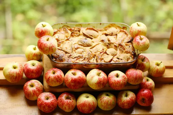 Кусочки свежего яблочного пирога среди сырых яблок в стиле кантри — стоковое фото