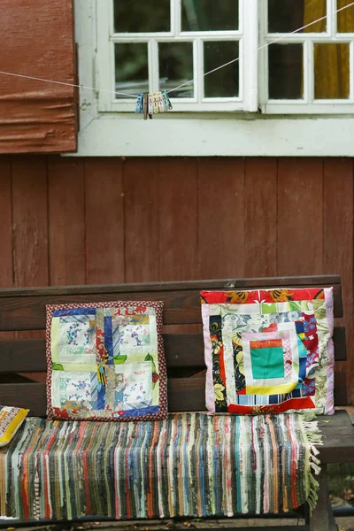 Travesseiros feitos à mão e tapete no banco de madeira pho país ao ar livre — Fotografia de Stock