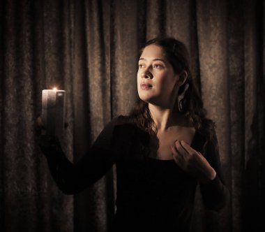 Mumlu genç bir kadının karanlık anahtar portresi. Yaklaş.