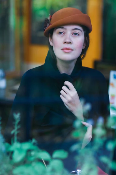 Retro porträtt av kvinna genom caféfönstret i hatt och rock — Stockfoto