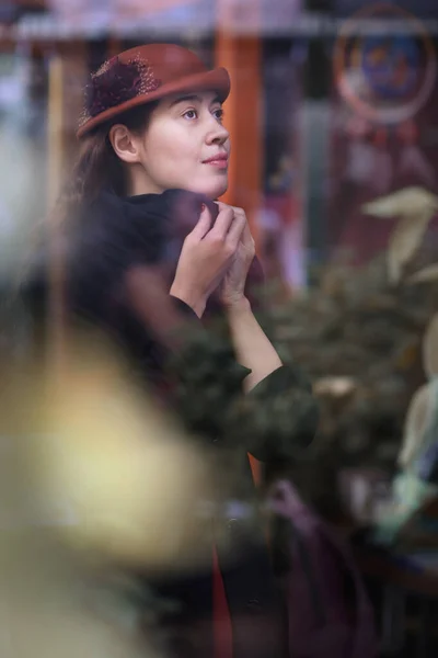 Retro portrait of woman through the cafe window in hat and coat — Stock Photo, Image