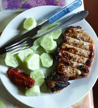 Kemik, salatalık, ketçap çatalı ve bıçakla kavrulmuş biftek tabağa yakın fotoğraf