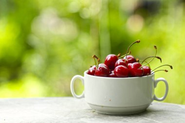 Sağlıklı kahvaltı - kasedeki tatlı kiraz yeşil çimen arka planda yakın fotoğraf