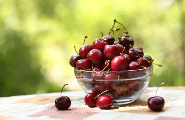  Tatlı kirazlar kasede. Yeşil çimen arka planda yakın fotoğraf.
