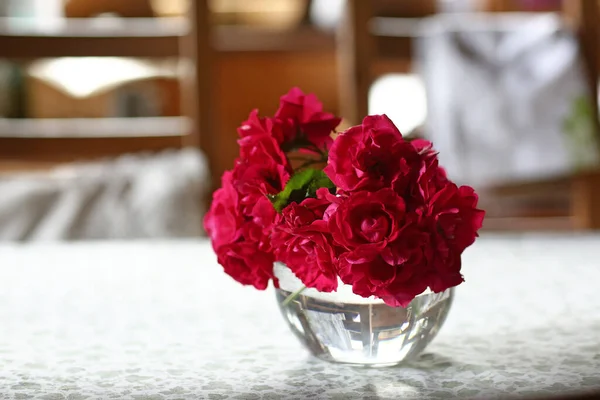 Rosas rojas en jarrón de cristal en la mesa blanca en el interior de la cocina de cerca foto — Foto de Stock