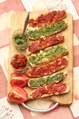 Acı biberli domates ve pesto sosu dilimlenmiş İtalyan ciabatta ekmeği bruschetta sandviçi pişirmek için mutfak tahtasına yakın fotoğraf çek.