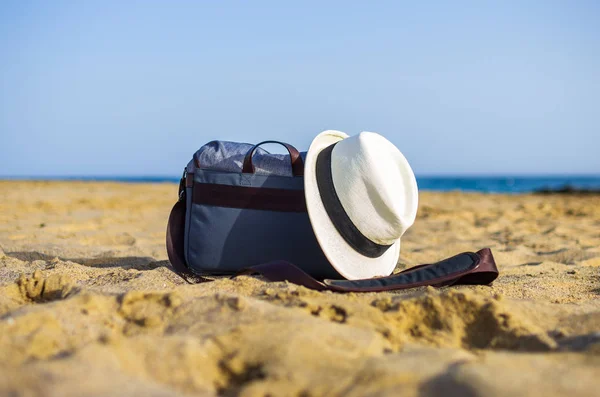 Shoulder bag and white hat on the sand of the beach