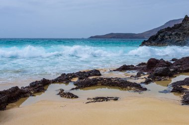 Playa de las Conchas sahilinde kayalara çarpan dalgalar