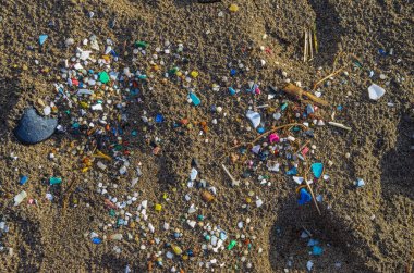 Micro plastics mixed in the sand of the beach clipart