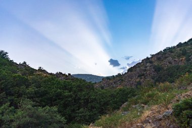 Gün batımında bir dağda gökyüzünde güneş ışınları