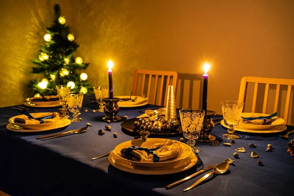 Karácsonyi asztal beállítása a karácsonyfát a háttérben — Stock Fotó