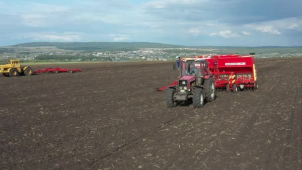 Červené traktory, odebrané z dronu, se navzájem pronásledují přes pole.. — Stock video