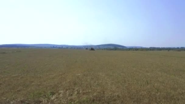 Afgenomen van een drone, rijdt een rode oogstmachine door een veld. Rusland, Bashkortostan — Stockvideo