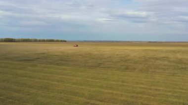 İnsansız hava aracından alınan kırmızı bir hasat aracı tarladan geçiyor. Rusya, Bashkortostan