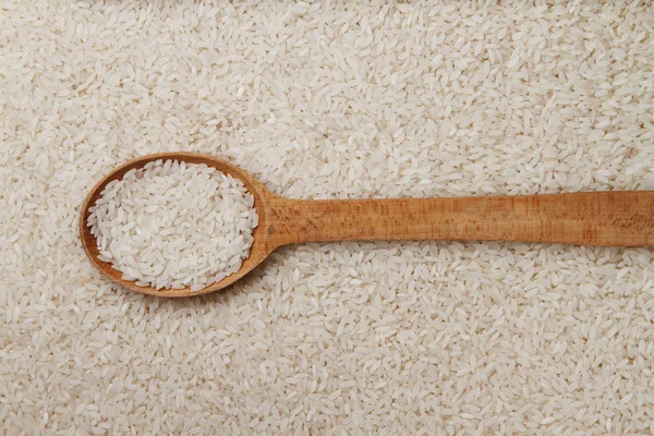 Raw rice in wooden spoon