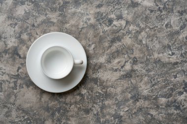Boş fincanın gri dokulu arka plandaki fincan tabağı üzerindeki üst görünümü             