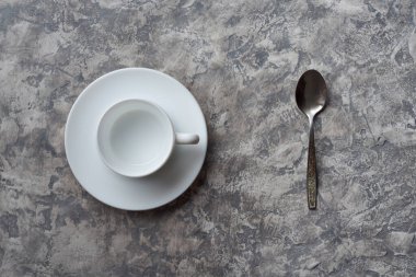 Gövde üzerindeki boş bardağın üst görünümü ve gri desenli arka planda kaşık