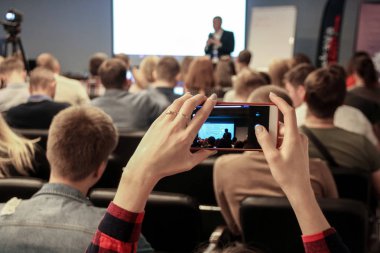Kadın akıllı telefon kullanarak konferans sırasında bir resim çeker