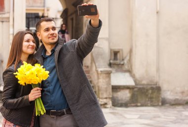 Sokakta selfie çeken çiçeklerle mutlu bir çift. Kopyalama alanı.