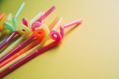 Sarı arka plana karşı renkli içme pipetleri