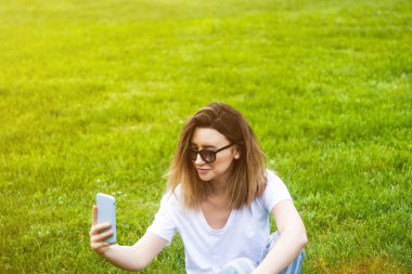 Akıllı telefonla parkta selfie çeken şık genç kadın