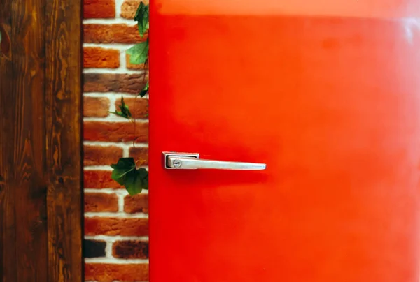 Retro vintage style red fridge against brick wall background