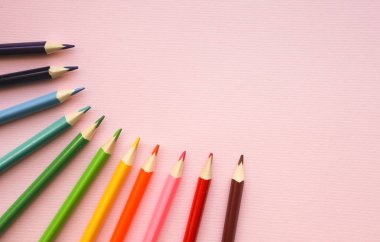 Pembe pastel arka planda gökkuşağı renklerirenkli kalemler