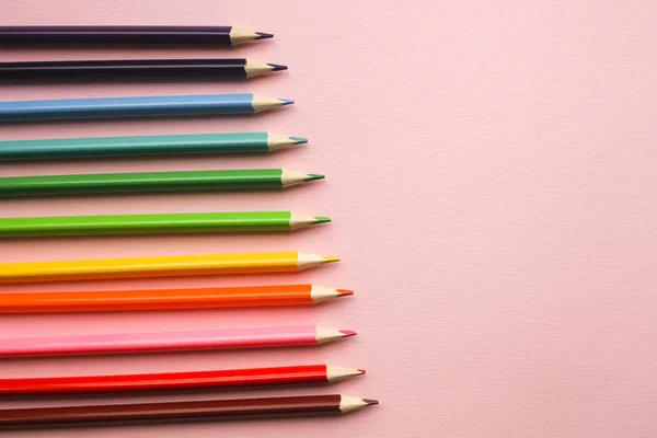 Colorful pencils of rainbow colors on pink pastel background
