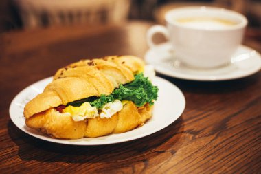 Restoran masasında salata ile kahve büyük beyaz fincan ve lezzetli kruvasan