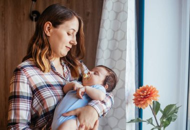 Evde elinde bebek ile genç kadın