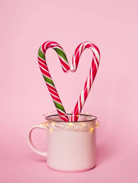 Pink Christmas picture of cup with two candies and lights. — Stock Photo, Image