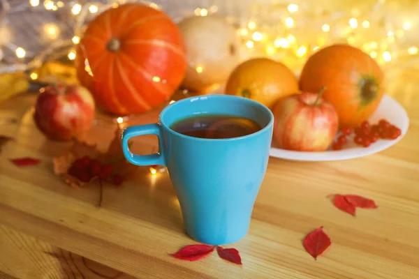 Cup of tea on wood table against blurred pumpkins, apples and autumn decorations on the window. — Stock Photo, Image