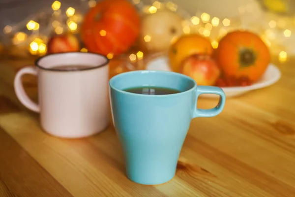 Two cups of tea on wood table against blurred pumpkins, apples and autumn decorations on the window. — Stock Photo, Image