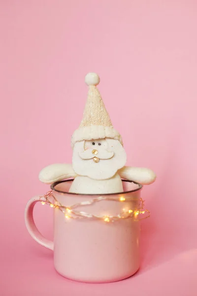 Christmas picture of cup with Santa toy and lights. — Stock Photo, Image