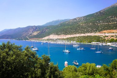 Önünde dağlar ve yatlar olan deniz manzaralı bir yer.